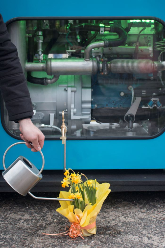 Motorpräsentation: Das Wasser als einziges Reaktionsprodukt des Zero-Emission-Kreislaufmotors ist so rein, dass Blumen damit gegossen werden können. Abbildung: IMG