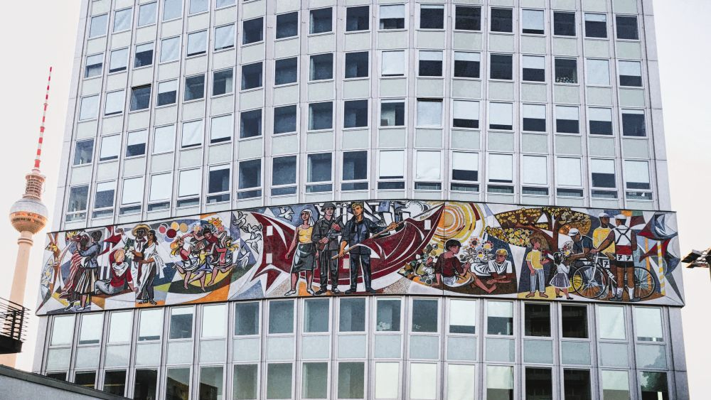 Sozialistischer Realismus: Das Mosaikfries „Unser Leben“ von Walter Womacka ziert das „Haus des Lehrers“ am Alexanderplatz in Berlin. Abbildung: Ndiggity, Wikimedia Commons